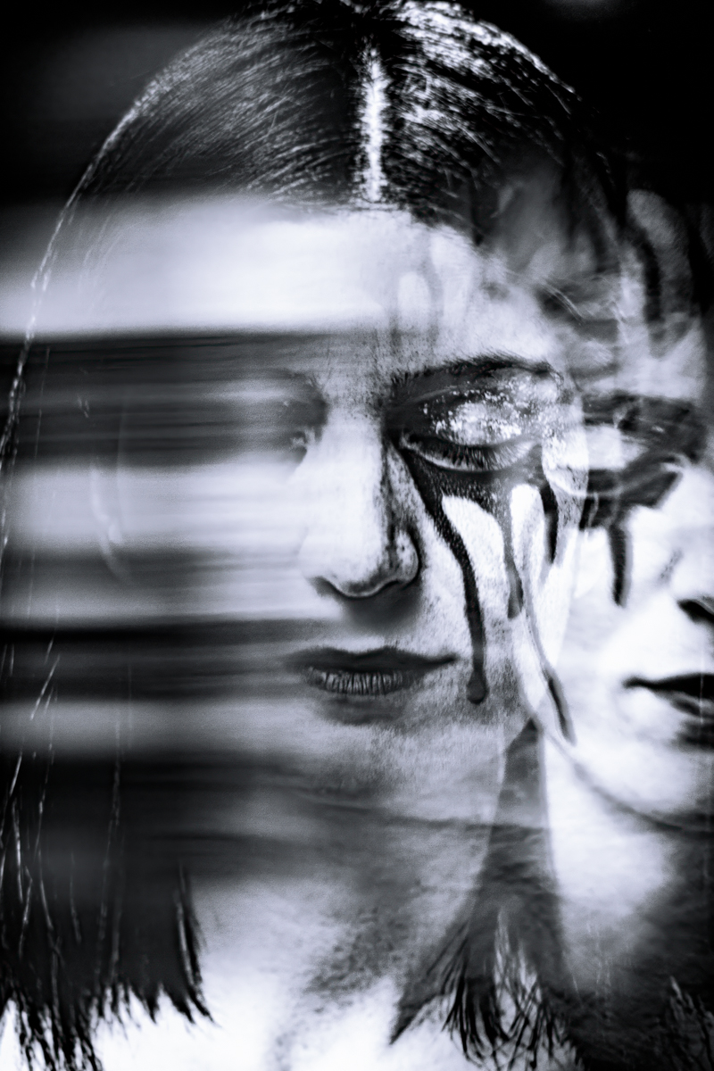 Double exposure black and white photo of a woman's face with dark makeup tears, creating an eerie and surreal effect.