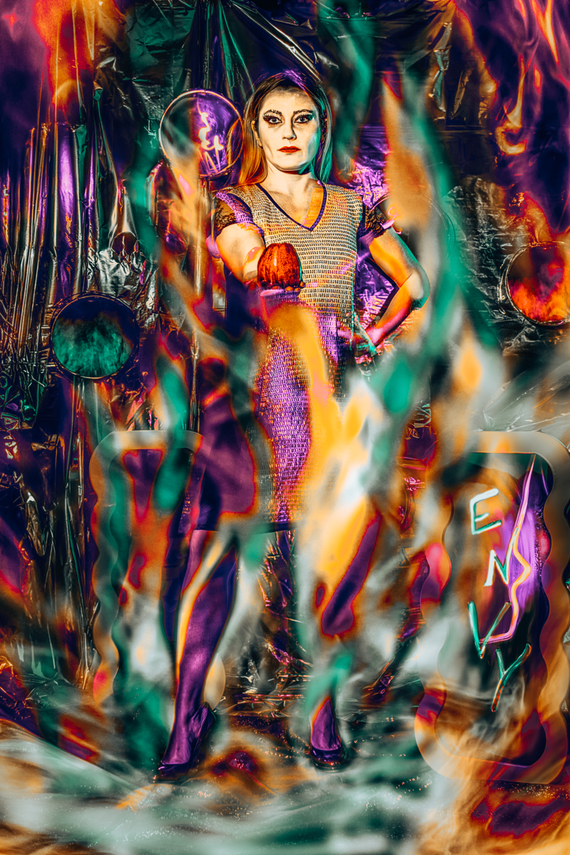 A woman in a shimmering silver gown holds a glowing orb, reflecting a stormy sky, representing the Queen from Whitesnow tale, and embodying the sin of envy.